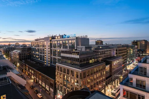 Stadtansicht bei Sonnenuntergang mit modernen Gebäuden und beleuchteten Straßen.