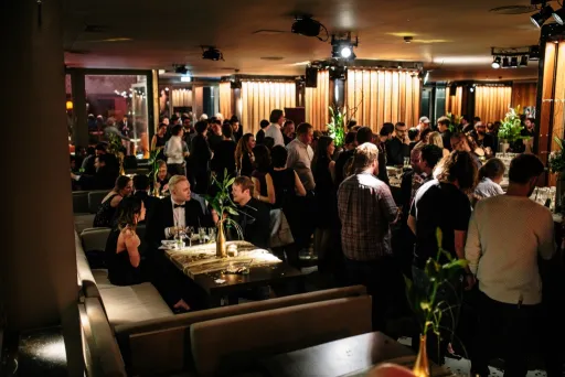 Viele Menschen in eleganter Kleidung feiern abends in einem stilvollen Restaurant.