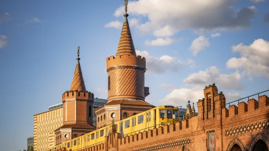 Gelbe U-Bahn fährt über die Oberbaumbrücke in Berlin bei Sonnenschein.