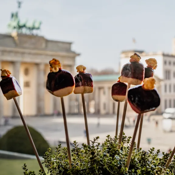 Spieße mit Käse und Trauben, im Hintergrund das Brandenburger Tor in Berlin.