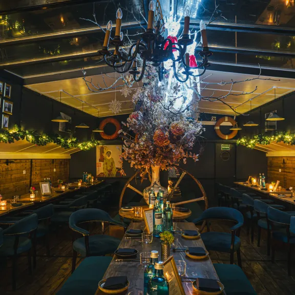 Stimmungsvoll beleuchtetes Restaurant mit festlich gedeckten Tischen und Kronleuchter.