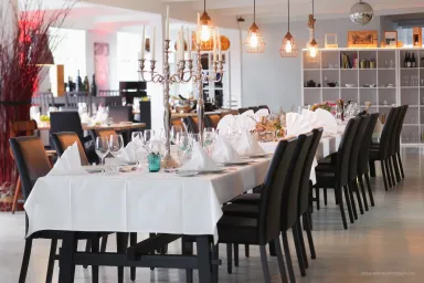 Elegant gedeckter Tisch in modernem Restaurant mit weißen Tischdecken und schwarzen Stühlen.